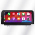 In-car infotainment touchscreen displaying app icons (Phone, Music, Maps, Messages, Now Playing) on a colorful home-screen grid in a black dash mount, with mounting brackets visible below.