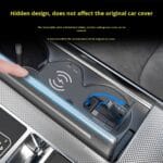 Close-up of a car’s center console showing a hidden retractable charging cable under a cover; a finger points to a wireless charging pad with blue arrows indicating the cable being tucked away, and yellow text stating the hidden design does not affect the original car cover.