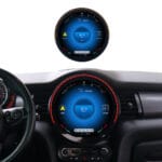 Car dashboard with a circular digital gauge showing 87.5 MHz radio and navigation icons central to the display.
