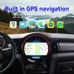 Center car dashboard with a built-in GPS navigation map on the touchscreen, mountains visible through the windshield.