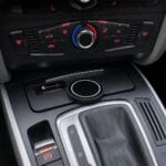 Center console showing a climate control panel with a red/blue temperature dial, a round wireless charging pad, and a gear shifter with leather cover nearby.