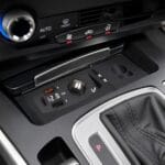 Center console of a car with USB-C and USB-A charging ports, 12V/VIA, cup holder, and gear shifter nearby